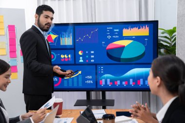 Pazarlama stratejisi için modern toplantıda veri analizi paneli ekranında sunan bir işadamı. Bir grup iş adamıyla konferans odasında iş sunumu. Uyum