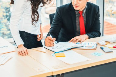 İki iş adamı toplantı odasında proje stratejisi hakkında konuşuyor. İş adamı, iş yerinde iş arkadaşlarıyla proje planlamasını tartışırken aynı zamanda mali raporla ilgili sohbet ve tavsiyelerde bulunuyor. Jivy