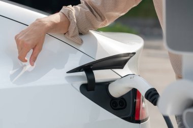 Kapalı el, şehrin park alanındaki şarj istasyonundan elektrikli araba aküsünü şarj etmek için EV şarj aleti yerleştirdi. Sürdürülebilir çevre dostu şehir yolculuğu için şarj edilebilir EV araba. Yararlı