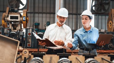 Metal imalatında makine mühendisliği denetleyicisi olarak liderlik örneğini sunan çelik endüstriyel makineyi incelemek için dizüstü bilgisayar kullanan fabrika mühendisi ve asistan..