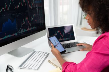 Ciddi yüzlü Afrikalı kadın blogcu, ekran ekranına bakıyor ve borsa başarısı yüksek olan akıllı telefona bakıyor. Çevrimiçi bilgisayar ticaretinde döviz yatırımı kavramı. Tatlandırıcı.