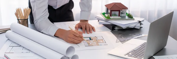 Interior architect designer at workstation table designing house interior blueprint and choosing mood board samples. Creative hand drawing sketch plan for house renovation or design concept. Insight