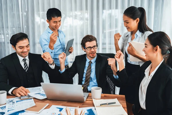 Group of happy businesspeople in celebratory gesture and successful efficient teamwork. Diverse race office worker celebrate after made progress on marketing planning in corporate office. Meticulous