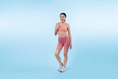 Spor giyim portresindeki tüm vücut Asyalı kadın gülümsüyor ve neşeli bir jest yapıyor. Çekici bir kızla egzersiz yapmak sağlıklı yaşam tarzını sürdürmeye yöneliktir. İzole edilmiş arka plan Vigorous