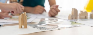 Profesyonel mimar mühendis takımı toplantı masasında ahşap blokla ve etrafa saçılmış planlarla mimari projeyle ilgili tartışır. Tasarım ve işbirliği konsepti. - Yakın çekim. Tanımlama.