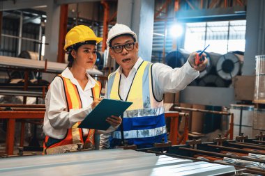 Fabrika mühendisi, metal levha ürünü üzerinde kalite kontrolü yapmak ve ağır endüstriyel çelik damgalama veya oluşturma makinesini denetlemek için iş arkadaşıyla işbirliği yapar. Örnek gösteriliyor