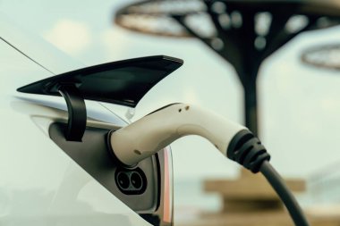 Kapalı EV şarj kolu fişe takıldı veya elektrikli arabaya bağlandı, EV araba aküsünü temiz çevre için sıfır CO2 emisyonu ile alternatif ve sürdürülebilir enerjiyle şarj etti. Kalıcı