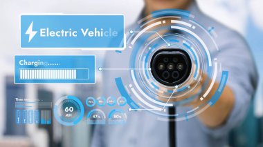 Kameranın önüne odaklanmış EV şarj cihazı bulanık şehir manzaralı akıllı dijital batarya durum hologramını gösterir. Alternatif temiz enerji kullanan EV araba şarjı CO2 salınımını azaltıyor. İnceleyin