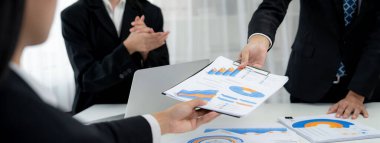 Grup toplantısındaki iş adamları resmi kıyafet paylaşımı fikrine sahipler. Şirketin yaratıcı çalışma alanındaki kar raporunu tartışıyorlar. Grup toplantısı masasında yakın çekim yapmak için. Konuşma .