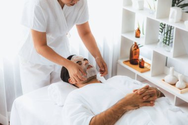 Kaplıca salonunun sakin, modern gündüz atmosferi. Kadın müşteri yüz maskesi takarak kendini yenilemeye çalışıyor. Yüz bakımı ve güzellik kozmetolojisi prosedürü. Sessiz.