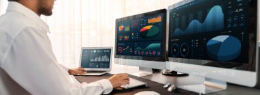 Analizci veri analizi ya da bilgisayar monitöründeki BI gösterge paneli üzerinde çalışıyor. Ticari pazarlama ve strateji planlaması için Fintech 'in şirket ofisindeki finansal verilerini analiz eden bir işadamı. Önde.