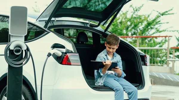 Menino Sentado Porta Malas Carro Usando Tablet Enquanto Recarrega Carro — Fotografia de Stock