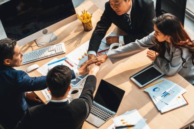 Mutlu iş adamları takım çalışmasının başarısını kutlarken ofis masasında yukarıdan çekilen neşeyle kutluyorlar. Genç işadamı ve işkadını işçiler, neşeli zafer gösterisi birliği desteği gösterdiler. Jivy