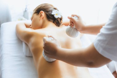 Sıcak bitkisel top spa masaj vücut tedavisi, masör kadın vücuduna nazikçe şifalı bitki torbası bastırıyor. Aromaterapi dinlenme sükuneti ve sükuneti kaplıca salonundaki atmosferi aydınlatıyor. Sessiz.