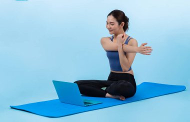 İnternetteki videodan alınan talimatlara göre spor kıyafeti giymiş genç Asyalı bir kadın spor egzersizinden önce geriniyor. Sağlıklı atletik bir kadınla vücut egzersizi izole bir zeminde ısınıyor. Kuvvetli