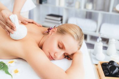Sıcak bitkisel top spa masaj vücut tedavisi, masör kadın vücuduna nazikçe şifalı bitki torbası bastırıyor. Aromaterapi dinlenme sükuneti ve sükuneti kaplıca salonundaki atmosferi aydınlatıyor. Sessiz.