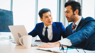 İki iş adamı toplantı odasında proje stratejisi hakkında konuşuyor. İş adamı, iş yerinde iş arkadaşlarıyla proje planlamasını tartışırken aynı zamanda mali raporla ilgili sohbet ve tavsiyelerde bulunuyor. Jivy