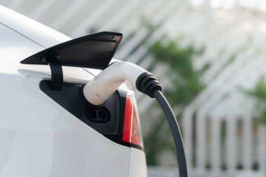 Kapalı el, şehrin park alanındaki şarj istasyonundan elektrikli araba aküsünü şarj etmek için EV şarj aleti yerleştirdi. Sürdürülebilir çevre dostu şehir yolculuğu için şarj edilebilir EV araba. Yararlı