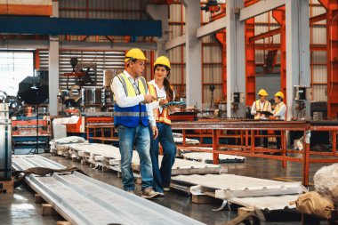 Fabrika ustabaşı ve mühendis çelik makinesi ve ağır endüstriyel malzeme kalitesinde ürün teftişi yapıyor. Makine güvenliği ve kalite kontrollü metal levha üretimi. Örnek gösteriliyor