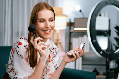 Kadın Etkilenen Vlog video görüntülerini sosyal medya ya da blog 'da en üst düzeyde yayınlıyor. Kozmetik stüdyosu ışıklandırmalı mutlu genç kız çevrimiçi pazarlama oturumu yayını için..