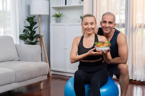 Healthy senior couple in sportswear with a bowl of fruit and vegetable. Healthy cuisine nutrition and vegan lifestyle for fitness body physique concept. Clout