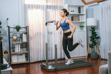 Enerjik ve güçlü atletik Asyalı kadın evde koşu makinası çalıştırıyor. Formda fiziğin takibi ve ev çalışması ve eğitimle sağlıklı yaşam tarzına bağlılık. Kuvvetli