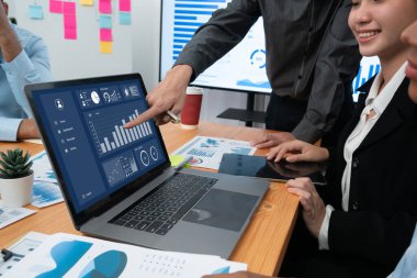 Çok ırklı analist ekibi toplantı masasındaki finansal verileri analiz etmek için BI Fintech yazılımı kullanıyor. Finansal konsol veri ekranında pazarlama göstergesi için analiz edilmiş grafikle birlikte. Uyum