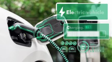 Elektrikli araba, doğal parktaki temiz enerji şarj istasyonundan gelen fütürist akıllı EV şarj cihazının dijital batarya durumu hologramıyla şarj oluyor. Gelecekçi çevre dostu EV araba. İnceleyin