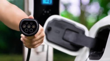 Kameranın önüne odaklanmış EV şarj cihazı fütüristik akıllı dijital EV batarya durum hologramını gösteriyor. EV araba şarjı sürdürülebilir güç için alternatif enerji kullanıyor. İnceleyin
