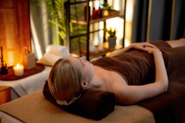Beyaz kadın müşteri stres önleyici spa masajının keyfini çıkarıyor ve lüks otel ya da otelde sıcak mum ışığında güzellik teniyle eğleniyor. Sessiz.