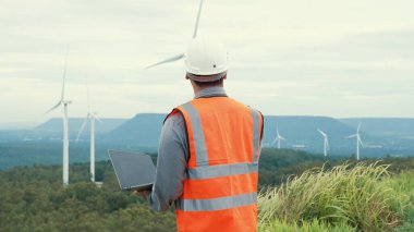 Kırsal kesimdeki bir tepenin tepesinde ya da dağda rüzgar çiftliğinde çalışan bir mühendis. Yenilenebilir ve sürdürülebilir enerjinin gelecekteki üretimi için yenilikçi bir ideal. Rüzgar türbininden enerji üretimi.