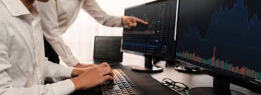 Bir grup tüccar ofis masasında tartışıyor, borsayı işyerinde monitörden izliyorlar. İşadamı ve borsacı borsa şirketinde hisse senedi grafiğini birlikte analiz ediyorlar. Önde.