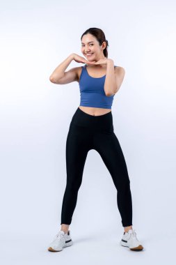 Spor giyim portresindeki tüm vücut Asyalı kadın gülümsüyor ve neşeli bir jest yapıyor. Çekici bir kızla egzersiz yapmak sağlıklı yaşam tarzını sürdürmeye yöneliktir. İzole edilmiş arka plan Vigorous