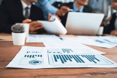 İş zekası grafiği, grafik ve istatistik raporlarını arka planda çalışan bulanık iş adamlarıyla ofis masasına odakla. Habiliment