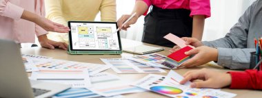 İç mimar ekibinin kırpılmış görüntüsü malzeme rengini tartışırken, tablet cep telefonu uygulaması ve web sitesi için web sitesi kablo tasarımı görüntüledi. Yaratıcı tasarım ve iş konsepti. Değiştirilmiş.