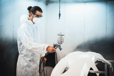 Koruyucu ekipmanlı otomotiv işçisi araba kaportasına sprey tabanca ya da oda atölyesindeki solunum boyasıyla renk boyası uyguluyor. Tamir için araba boyama servisi. Oxus.