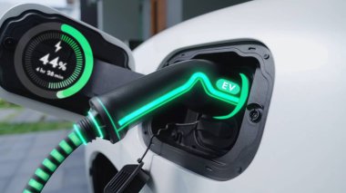 Ev şarj istasyonundaki EV şarj aleti fişe takılı ve dijital akü durum hologramını gösteren elektrikli arabayı şarj ediyor. Akıllı ve fütüristik ev enerjisi altyapısı. İnceleyin