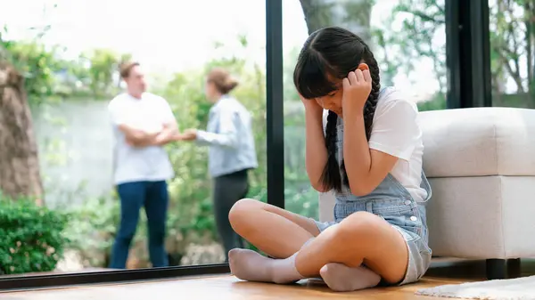 ストレスを受け 不幸な若い少女が角を曲がり 彼女の耳が彼女の親が背景で主張する音を遮断するのを隠している 自宅での家庭内暴力とトラウマ的な子供時代のうつ病 パノラマシンクロノス — ストック写真