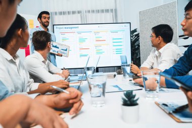 Proje yöneticisi monitörde proje yönetimi yazılım görüntülemesi, proje görevinin ilerlemesini izlemek ve toplantı masasında program planı yapmak suretiyle ekiple iletişim kurar ve işbirliği yapar. Tedbirli