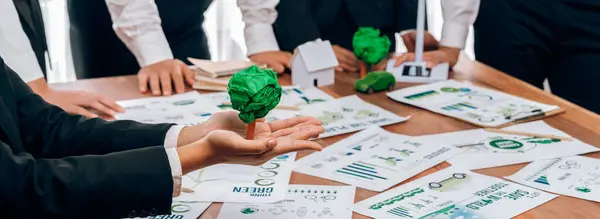 Green eco-friendly business people with environmental responsibility meeting on reforestation and alternative sustainable energy utilization. Businessman hold paper tree in meeting room.Trailblazing