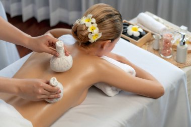 Sıcak bitkisel top spa masaj vücut tedavisi, masör kadın vücuduna nazikçe şifalı bitki torbası bastırıyor. Aromaterapi dinlenme sükuneti ve sükuneti kaplıca salonundaki atmosferi aydınlatıyor. Sessiz.