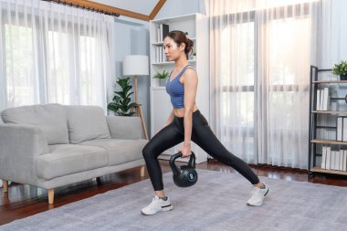 Enerjik kadın evde kettlebell ağırlık kaldırma egzersizi yapıyor. Genç atletik Asyalı kadın dayanıklılığı ve dayanıklılık antrenmanı. Ev ödevi olarak..