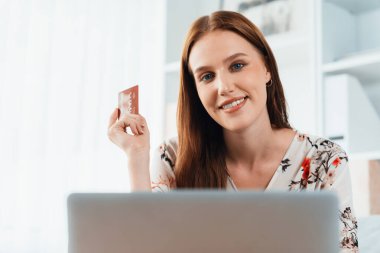 Genç mutlu kadın internetten alışveriş yaparak ürün satın alırken aynı zamanda internet üzerinden online ödeme sistemi ile çevrimiçi mağaza platformundan en yüksek siber güvenlik tarafından korunan ürünler sipariş ediyor.