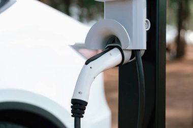 Kapalı EV şarj kolu fişe takıldı veya elektrikli arabaya bağlandı, EV araba aküsünü temiz çevre için sıfır CO2 emisyonu ile alternatif ve sürdürülebilir enerjiyle şarj etti. Kalıcı