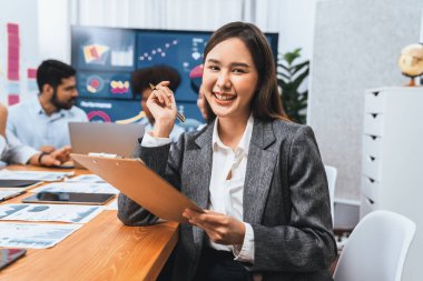 Bir grup ofis çalışanı ile birlikte arka planda ekran iş paneliyle buluşan mutlu Asyalı genç iş kadını portresi. Takım toplantısında kendine güveni tam bir ofis hanımı. Uyum