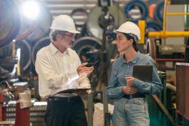 Metal imalatında makine mühendisliği denetleyicisi olarak liderlik örneğini sunan çelik endüstriyel makineyi incelemek için dizüstü bilgisayar kullanan fabrika mühendisi ve asistan..