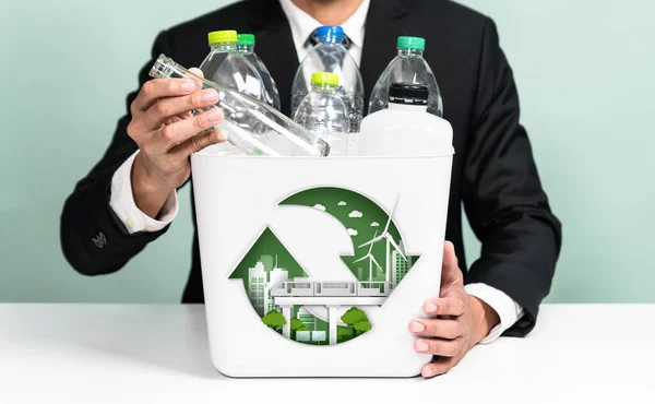 Eco friendly business with ESG commitment to make greener campaign with corporate recycling and waste management. Businessman hold recycle bin promoting sustainable clean environment. Reliance