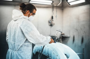 Koruyucu ekipmanlı otomotiv işçisi araba kaportasına sprey tabanca ya da oda atölyesindeki solunum boyasıyla renk boyası uyguluyor. Tamir için araba boyama servisi. Oxus.