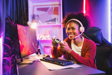 Afro-Amerikan oyun takımının galibi Esport ile online dövüş yapıyor. Neon ışıklı odada kulaklık takıyor. Rakiplerini kazanmak için strateji planlayan diğer oyuncularla konuşmak. Tatlandırıcı.