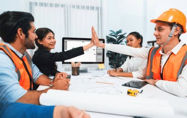 Çeşitli inşaat mühendisi ve müvekkil grupları, mimari proje üzerinde başarılı bir anlaşma yaptıktan, inşaat planını gözden geçirdikten ve toplantı masasında plan oluşturduktan sonra kutlama ve beşlik çakışma yaptılar.